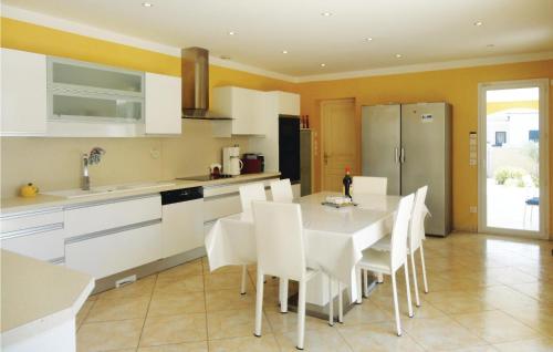 Una cocina con gabinetes blancos y una mesa y sillas. en 4 Bedroom Cozy Home In Grau D'agde, en Le Grau d'Agde