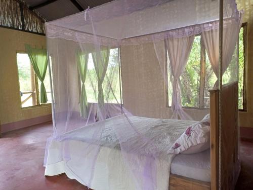 a bedroom with a canopy bed with mosquito nets at Nguse River Camp in Kikube