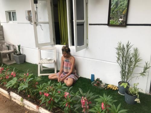 a woman sitting on the grass next to a house at White Barn Chalet in Ragama