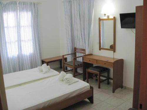 a room with two beds and a desk and a mirror at Tatsis Apartments in Masouri