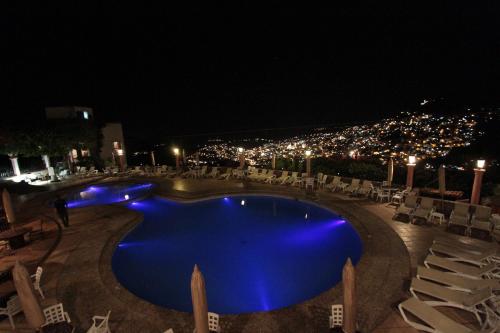a swimming pool at night with chairs and lights at Hotel Montetaxco in Taxco de Alarcón