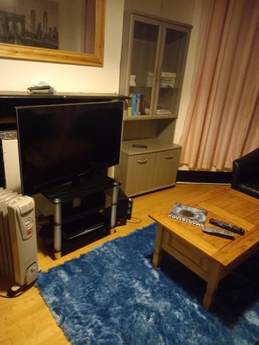 ein Wohnzimmer mit einem TV und einem Couchtisch in der Unterkunft Alistair lodge in Chatham