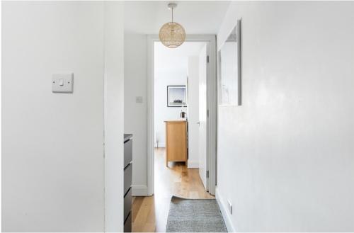 a hallway with white walls and a pendant light at Fabulous East Finchley in London