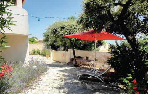 un parapluie rouge, une table et une chaise sous un arbre dans l'établissement Beautiful Apartment In Pignan, à Pignan