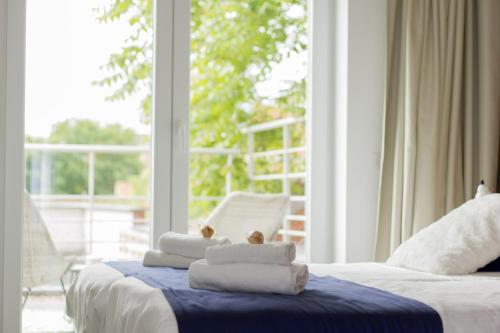 two beds with towels on them in a room with a window at Hotel Aan Zee in De Panne