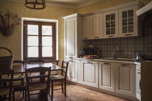 a kitchen with white cabinets and a table with chairs at La Bugia del Sensale in San Donato in Poggio