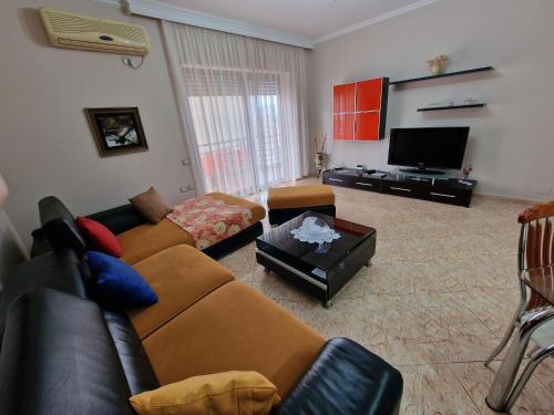 a living room with a couch and a tv at Apartament Orion in Vlorë