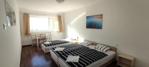 two beds in a small room with a window at Wesselényi Strand apartmanok in Balatonalmádi