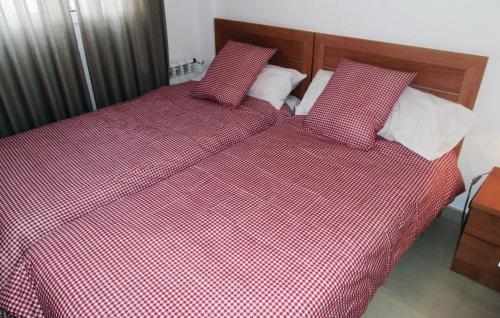 1 cama con edredón y almohadas rojos y blancos a cuadros. en Nice Apartment In Roldn With 2 Bedrooms, Internet And Outdoor Swimming Pool, en Los Tomases