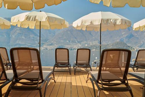 eine Gruppe von Stühlen und Sonnenschirmen auf einer Terrasse in der Unterkunft Hotel Villa Aurora in Lezzeno