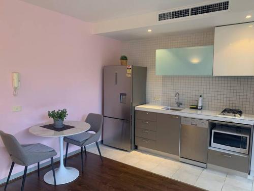a kitchen with a small table and a refrigerator at Light-filled apartment in a dream location 150m away from University of Melbourne in Melbourne