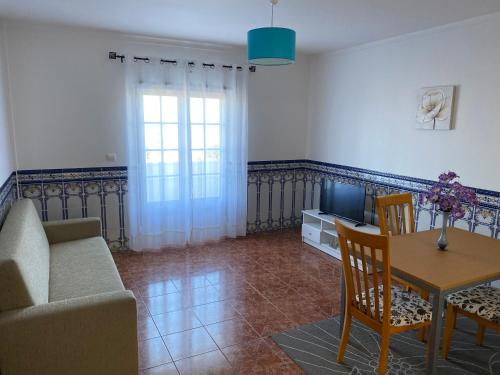 a living room with a couch and a table and a tv at Ericeira Sand Beach F7 in Ericeira