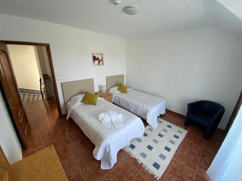 Cette chambre comprend 2 lits et une chaise bleue. dans l'établissement Ericeira Sand Beach F7, à Ericeira