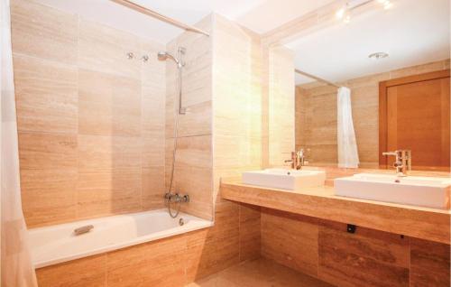 a bathroom with two sinks and a tub and a mirror at Stunning Apartment In Benahavs With Swimming Pool in Estepona