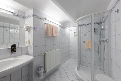 een witte badkamer met een douche en een wastafel bij Pension Elfy in Baden