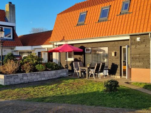 an orange roofed house with a table and chairs at Wulpenweid Bed & Parking in Den Burg
