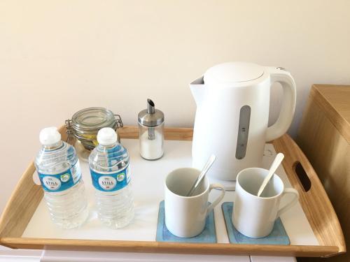a tray with cups and bottles of water and a coffee maker at Double room in the heart of Kingston upon Thames in London in Kingston upon Thames