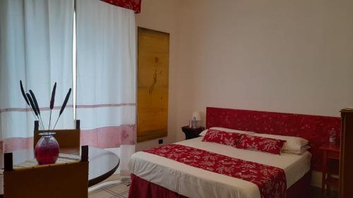a bedroom with a bed with a red headboard and a window at L'Indià Vittorio Affittacamere in Alghero