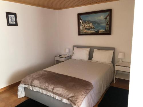 1 dormitorio con 1 cama y una pintura en la pared en LCC rooms, en Couço