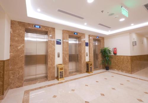 a lobby with two elevators and a potted plant at Sukoon Hotel in Al Madinah