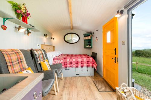 a bedroom in a tiny house with a bed at The Big Cwtch Shepherd's Hut in Kidwelly