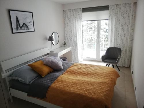 a bedroom with a bed and a chair and a window at Apartament Bukovy Wisła in Wisła