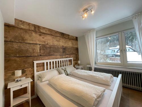 1 dormitorio con cama blanca y pared de madera en Ferienwohnungen Rothaarglück en Schmallenberg