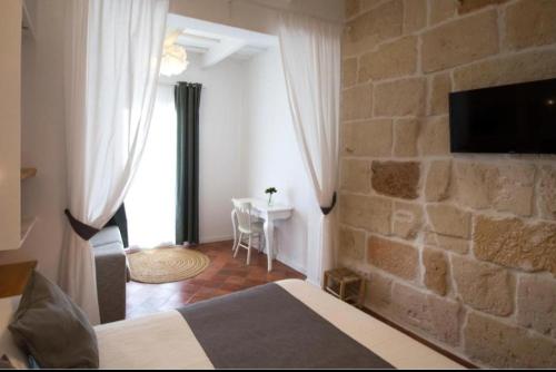 1 dormitorio con cama y pared de piedra en My Rooms Ciutadella Adults Only by My Rooms Hotels, en Ciutadella