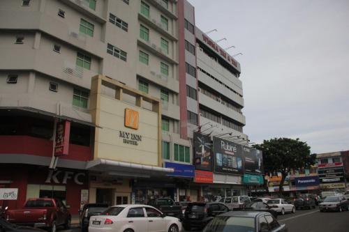een stadsstraat met auto's die voor een gebouw geparkeerd staan bij My Inn Hotel in Tawau