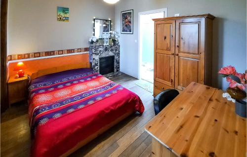 a bedroom with a bed and a table and a fireplace at Awesome Home In Morlaix With 3 Bedrooms in Sainte-Geneviève