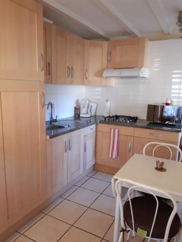 - une cuisine avec des placards en bois, une table et un évier dans l'établissement Gîte * Gaïa *, à Châtel-Montagne