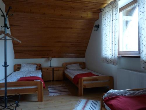 two beds in a room with wooden ceilings at Raduńska Ostoja in Dziemiany