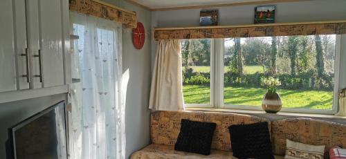 a living room with a couch and two windows at Rosebud Flower Farm Caravan Stay Countryside And Coast in Penzance
