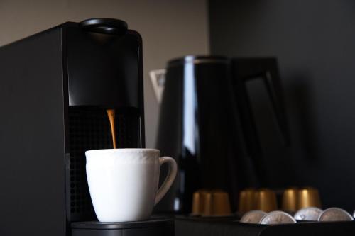 eine Kaffeemaschine und eine Tasse auf dem Tisch in der Unterkunft Cityzoe Athens Suites in Athen