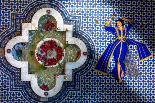 a painting of a woman in a blue dress on a wall at Riad Fes Nass Zmane in Fez