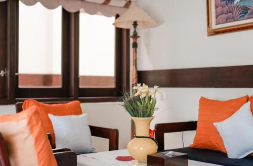 a vase of flowers on a table with pillows at Pasola Guest House in Medan