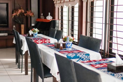 a dining room with tables and chairs with red and blue tablecloths at Pasola Guest House in Medan