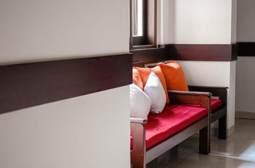 a bench with orange and white pillows on it at Pasola Guest House in Medan