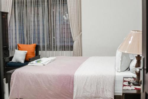 a bedroom with a bed and a chair and a window at Pasola Guest House in Medan