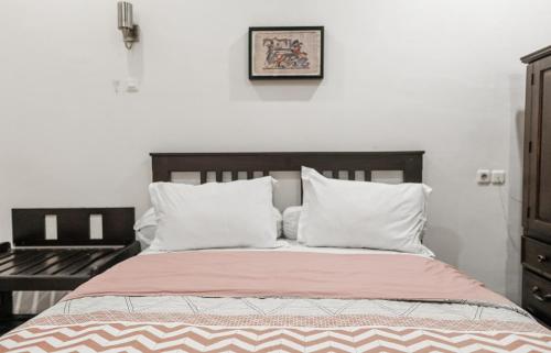 a bed with a wooden headboard and white pillows at Pasola Guest House in Medan