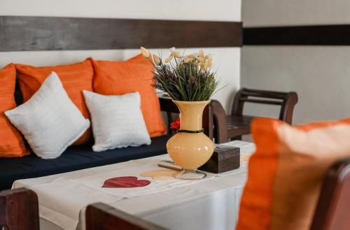 a vase with flowers on a table with a couch at Pasola Guest House in Medan