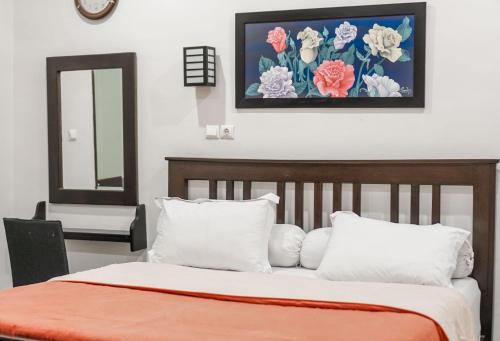 a bed with white pillows and a painting on the wall at Pasola Guest House in Medan