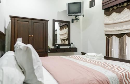 a bedroom with a bed and a tv on the wall at Pasola Guest House in Medan