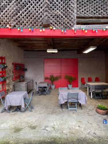 eine Terrasse mit Tischen und Stühlen und einer roten Wand in der Unterkunft Le 31 