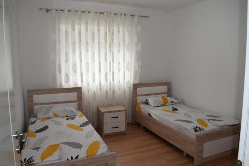 two twin beds in a room with white walls at Orchidea Apartment in Pogradec