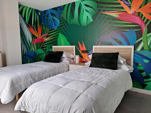 een slaapkamer met 2 bedden en een muurschildering van planten bij LEVANTE SUITES in Benidorm