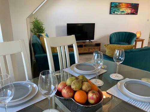 a table with a bowl of fruit and wine glasses at Luxurious Loft Flat 2-bed/2-bath in South Shields