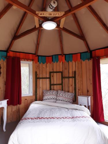 una camera da letto in una baita di tronchi con un letto in esso di LA HUTTE MASSAÏ a Villelaure
