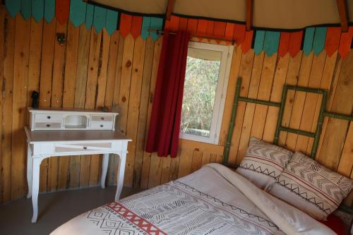 1 dormitorio con cama, escritorio y ventana en LA HUTTE MASSAÏ, en Villelaure