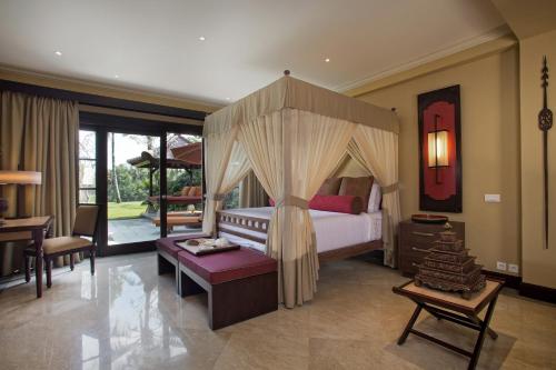 a bedroom with a canopy bed and a living room at Villa Senja in Tanah Lot